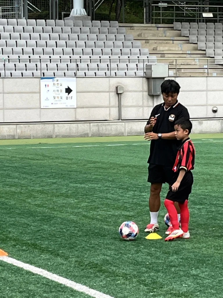 Coach FC Seoul Academy memberi instruksi kepada Kilian di lapangan kompleks Seoul World Cup Stadium